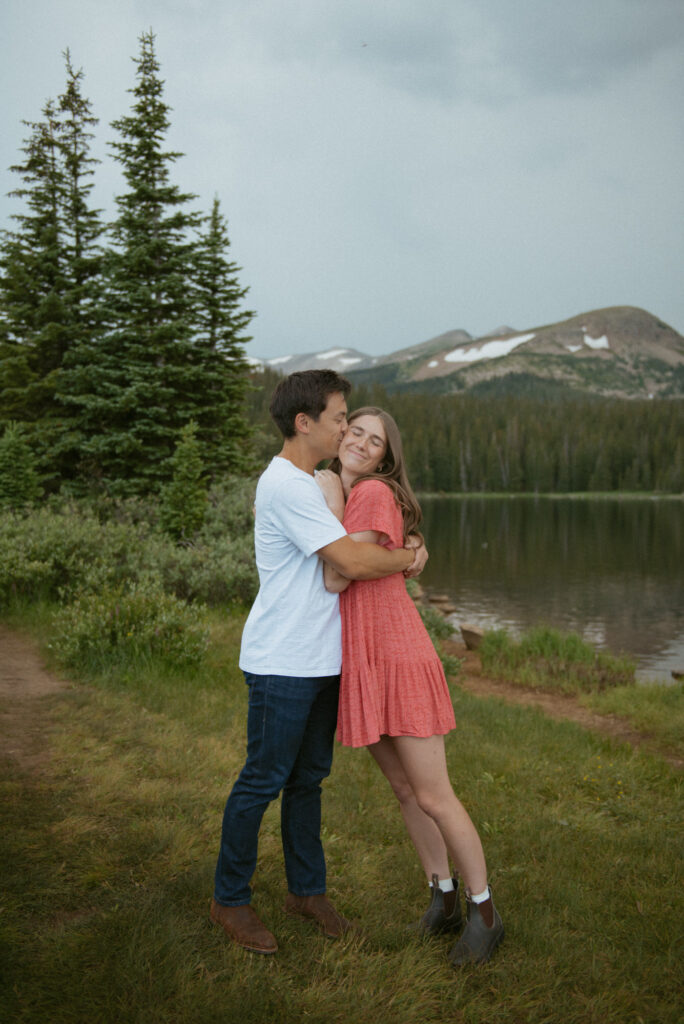A couple stands near the pines along Brainard Lake