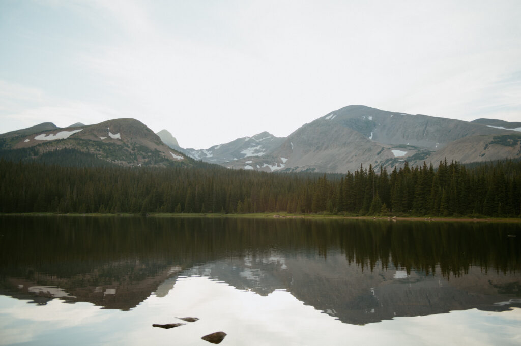 A serene photo of Brainard Lake, with the sun setting behind the peaks