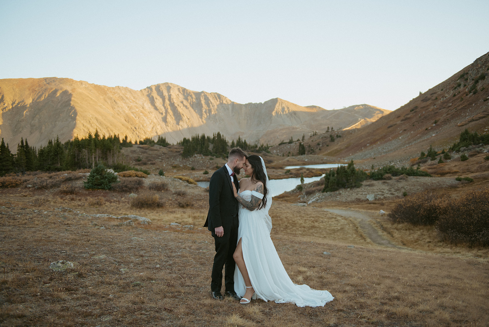 A couple standing in front of the mountains at an alpine lake during their Colorado elopement