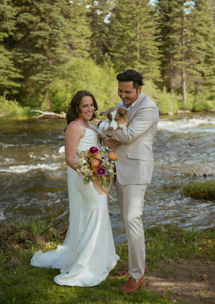 A couple with their dog by the river on their elopement day