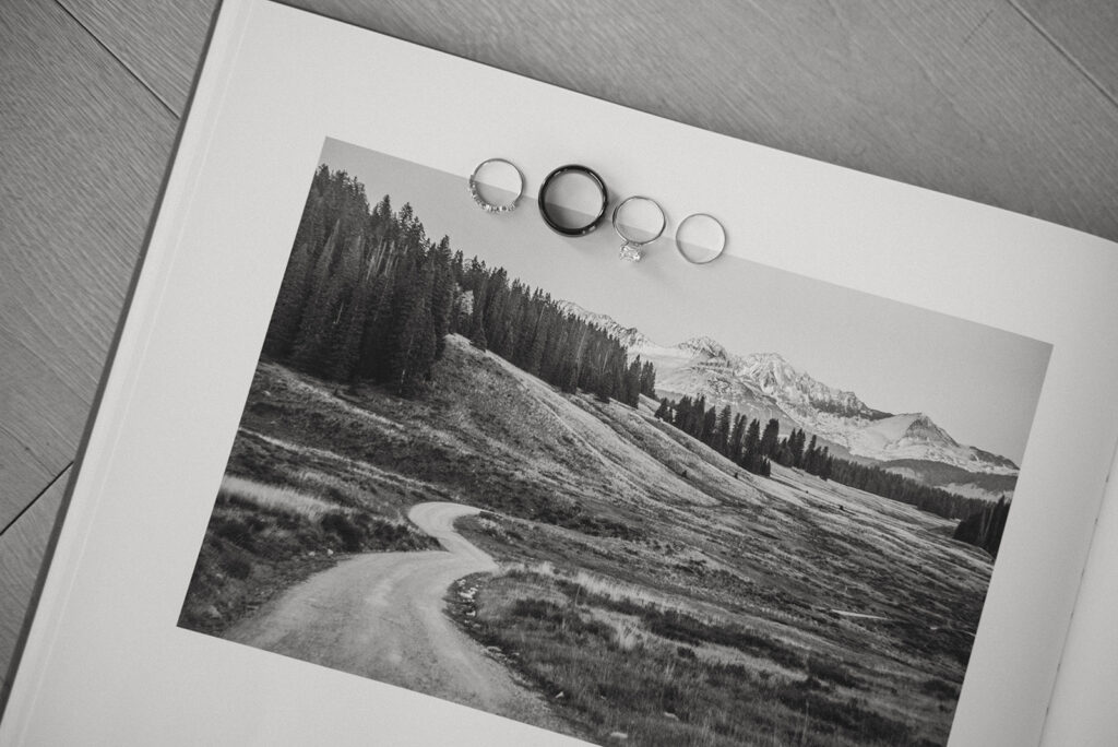 A couples rings sit on a book open to a photo of the Colorado mountains