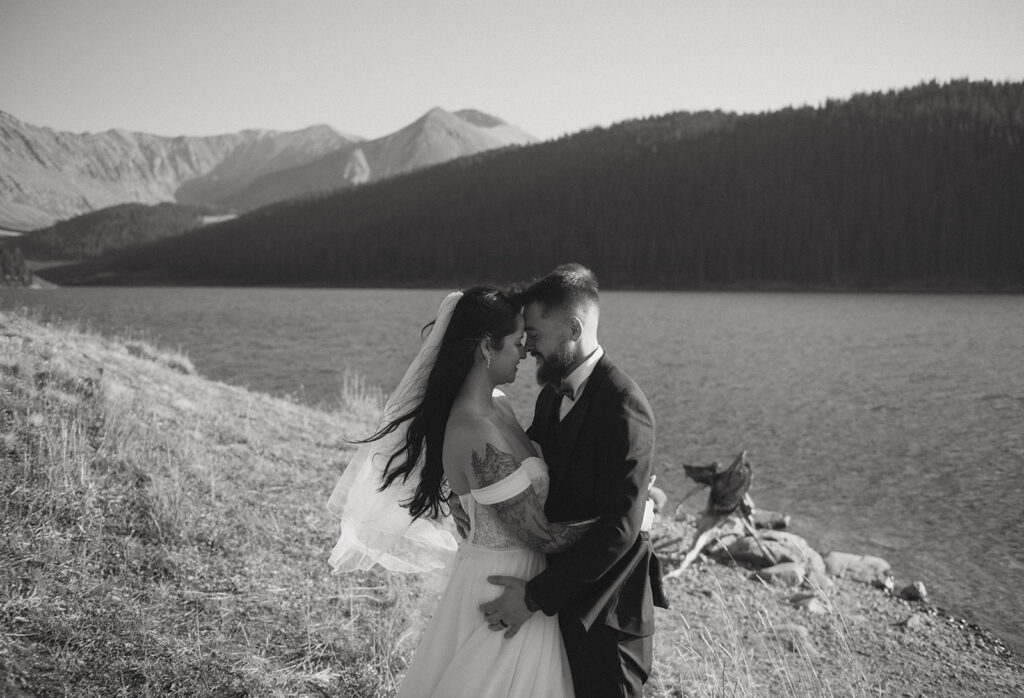 A couple stands by an alpine lake after their ceremony