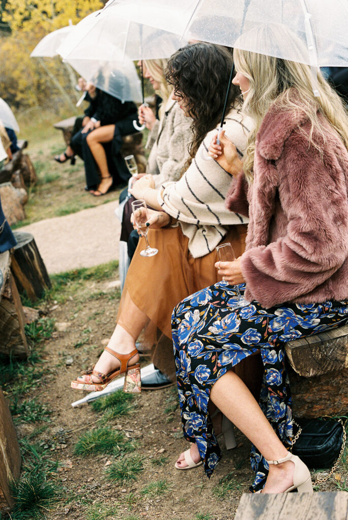 guests sitting under clear umbrellas during a colorado wedding